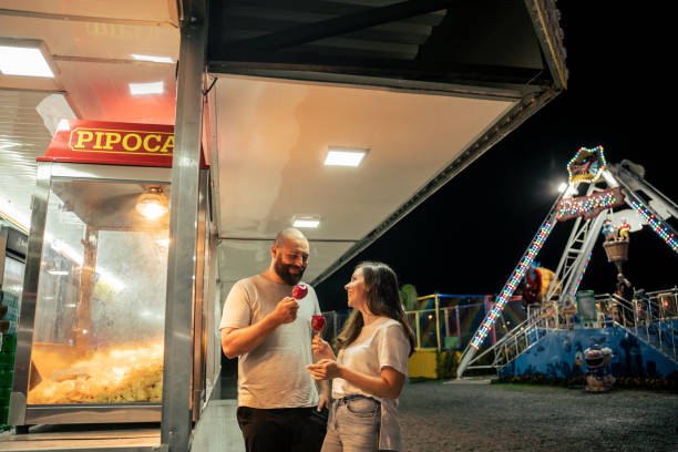 istock Young couple walking through amusement park at night 1946378702