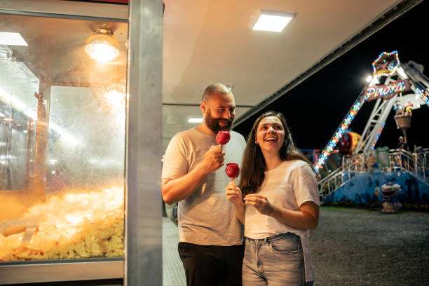 istock Young couple walking through amusement park at night 1946378711