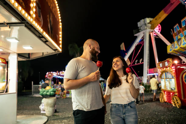 istock Young couple walking through amusement park at night 1946378821