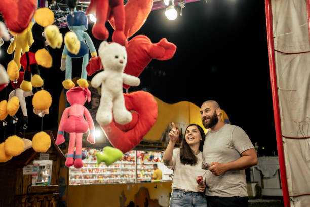 istock Young couple walking through amusement park at night 1946379798
