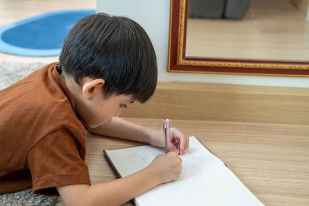 istock A little Asian boy was lying on the floor drawing on paper. 1946389721