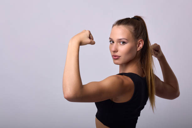 istock Young athlete in black uniform stands with back to hands, showing pumped biceps 1946417560