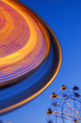 The lights of a spinning Ferris wheel at dusk