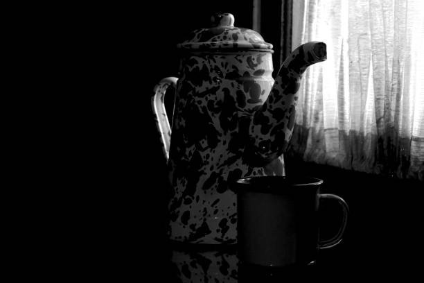 enamel teapots and cups that are on the table in a low light place