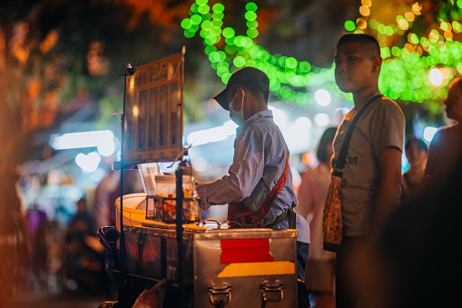 Bangkok, Thailand - January 12, 2024:
A Thai street vendor sells food on Khao San Road at night.