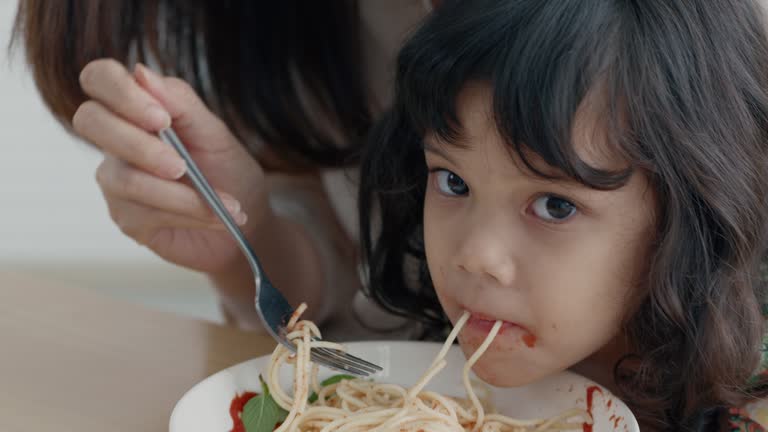 Motherhood feeding Spaghetti with daughter.