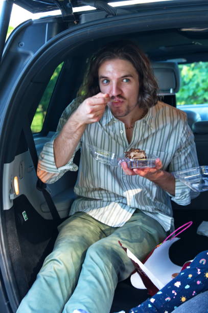 Man treats himself with sweet delicious glazed donut with hole outdoors
