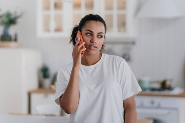 Woman in white tee using phone, concerned look