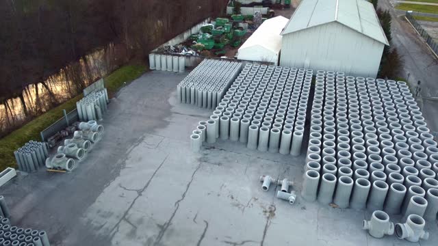 Aerial view of an industrial storage area with neatly arranged stacks of concrete pipes.