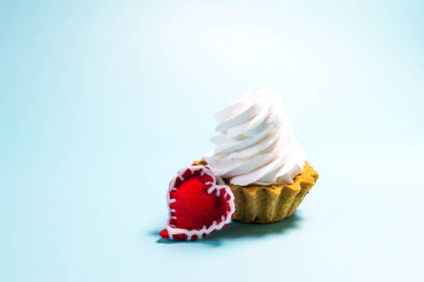 A fresh cake with an airy cream and a red heart on a light background is a place for text.
