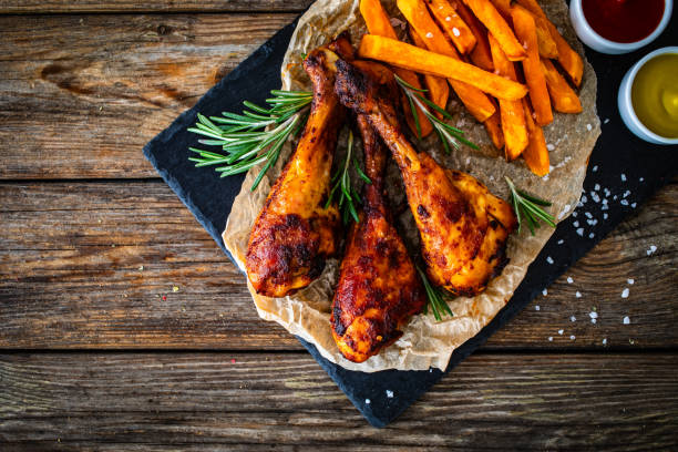roasted chicken drumsticks with sweet potatoes french fries  and ketchup, mayonnaise, mustard on wooden table - roast chicken barbecue chicken french fries chicken fotografías e imágenes de stock