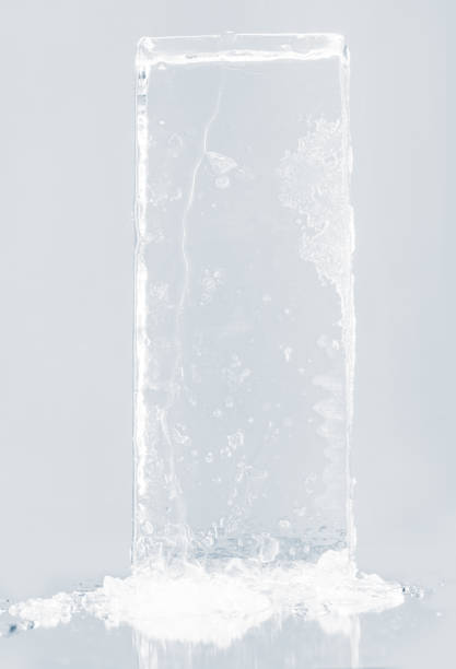 istock Crystal clear natural ice block in light blue tones on a white reflective surface. 1946878349