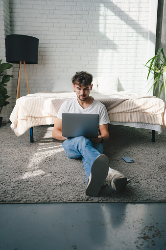 Man with laptop sitting on warm floor in living room. Heating system