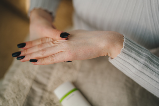 Young beauty asian woman applying hand cream at home. Rubbing nourishing body lotion. Beautiful young lady.