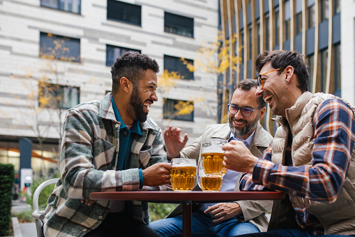 Men at social gatherings: group of friends drinking beer at the pub together