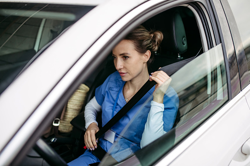 Female nurse going home from work, getting into car. Female doctor driving car to work, on-call duty. Work-life balance of healthcare worker as parent and partner.