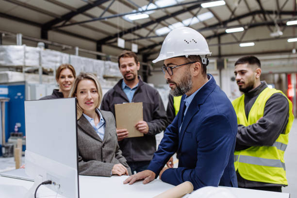 istock Manager presenting project to full team of warehouse employees on computer. Team of workers, managers, female director in modern industrial factory, heavy industry, manufactrury. 1947038941