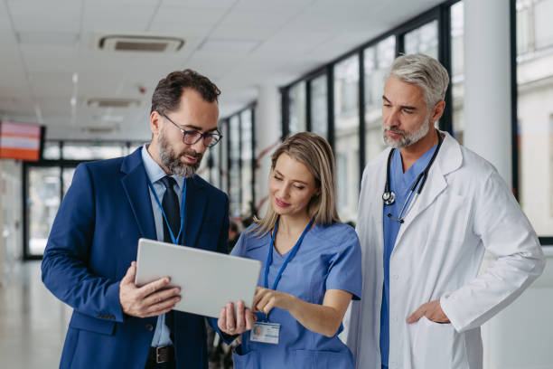 istock Pharmaceutical sales representative talking with doctors in medical building, presenting new product on tablet. 1947049080