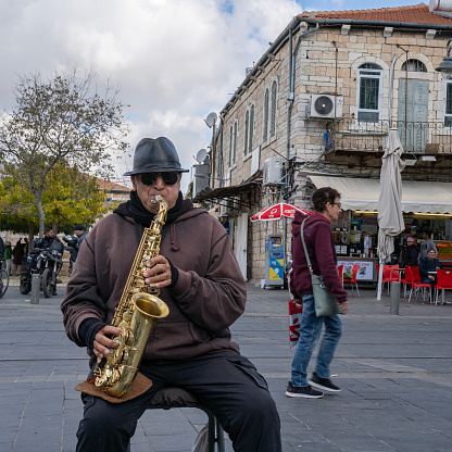 A man playing saxophone on a street in central Jerusalem, Israel.