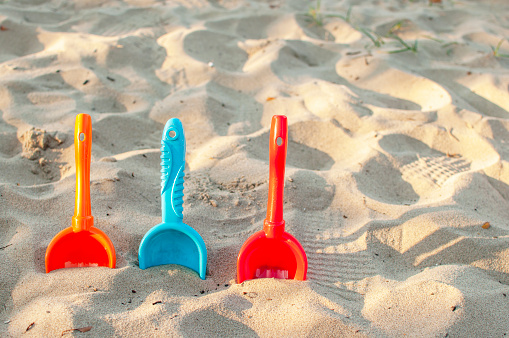 a red, orange and blue baby spatula on the beach on sunset
