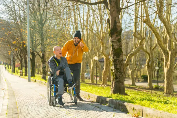 Photo of Caregiver pointing ahead talking to disabled man in a park