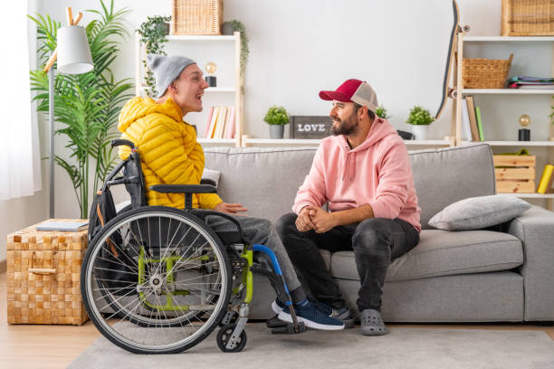 車椅子の障害者と自宅でリラックスしておしゃべりする友人 - help assistance support dependency ストックフォトと画像