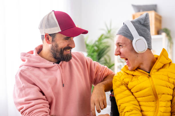 excited disabled man listening to music using headphones with friend - motorized wheelchair audio imagens e fotografias de stock