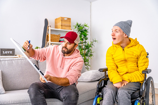 Man teaching to a disabled man using a white board at home