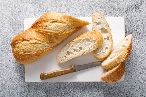 Bread, baguette sliced on a board, top view