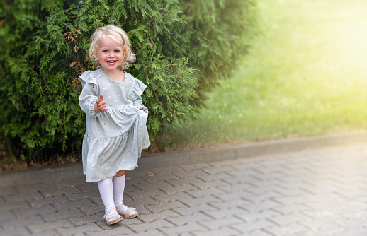 A side view of a young girl standing in an agricultural field and looking down.