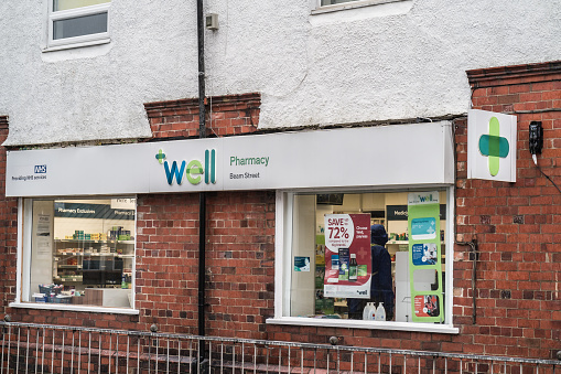 Nantwich, Cheshire, England, December 27th 2023. Well Pharmacy store with NHS branding, featuring a green cross symbol and sale posters in window.