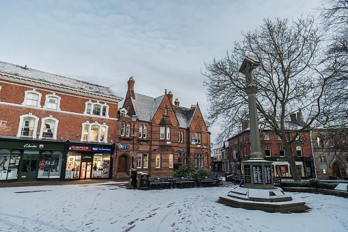 Nantwich, Cheshire, England, January 16th 2024. A snowy winter morning scene of Nantwich Town Center square, with storefronts in the background.