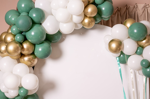 Arch of white, gold and green balloons on a white background
