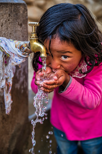 Nepalese girl drinking water,, Lo Manthang, Upper Mustang. Mustang region is the former Kingdom of Lo and now part of Nepal,  in the north-central part of that country, bordering the People's Republic of China on the Tibetan plateau between the Nepalese provinces of Dolpo and Manang.
