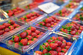 Fresh strawberries are arranged in plastic boxes, ready for sale at the farmers' market.