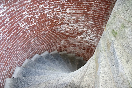 Architecture of a large spiral staircase with beautiful sunlight from outdoor, seen from below inside one of the bell towers of the Basilica Notre Dame de Fourviere. The Basilica was built between 1872 and 1884 with Byzantine and Romanesque architecture style, in a dominant position overlooking the city of Lyon, and dedicated to the Virgin Mary. It features fine mosaics and superb stained glass very ornate with gold and some paintings on the ceiling. This image was taken inside this famous place of worship monument in Lyon city, in Rhone department, Auvergne-Rhone-Alpes region in France (Europe), on Fourviere hill.