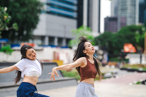 Two young Chinese women performing dance challenge for social media on the street.