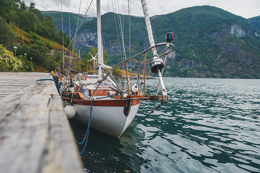 A yacht boat parked at a wooden pier on the shore of a fjord in Norway. Beautiful Scandinavian landscape