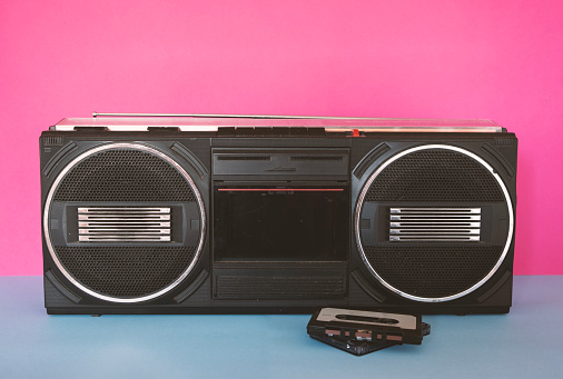 A vintage boom box on an 80s color pallet of yellow, pink and blue.