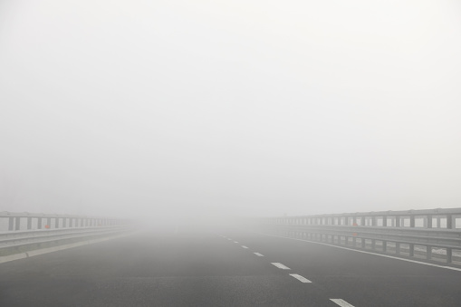 motorway without cars but with a lot of dangerous fog which reduces visibility