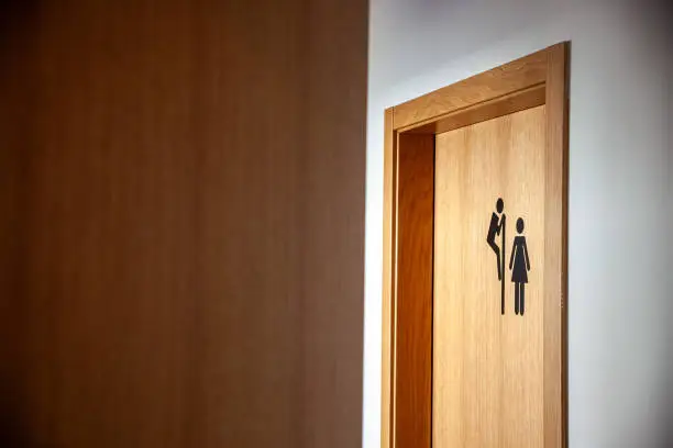 Unique restroom sign at a hotel: a man peeking over the door to the ladies' room. A playful and unexpected twist, perfect for creative and humorous concepts.