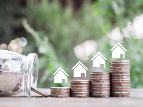 Miniature house icons and stack of coins. The concept of saving money for house, Property investment, House mortgage, Real estate.