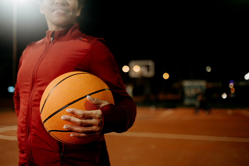 The photo captures a mature woman, looking away in the midst of a basketball game, her expression one of pure enjoyment and vitality, showcasing the enduring spirit and health benefits of participating in sports activities