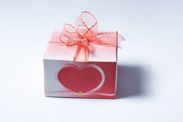 Red present with heart shape on white background with customizable space for text. Copy space.