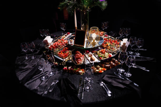 Festive tables with decor on black tablecloth and snacks ready for event
