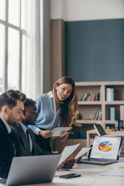 istock Three smiling business people analyzing charts and using laptop while working in the office together 1947497653