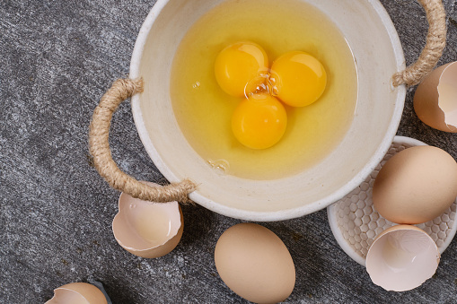 Whole eggs, broken eggs, yolk in a bowl on the table. Selective focus. Flat lay