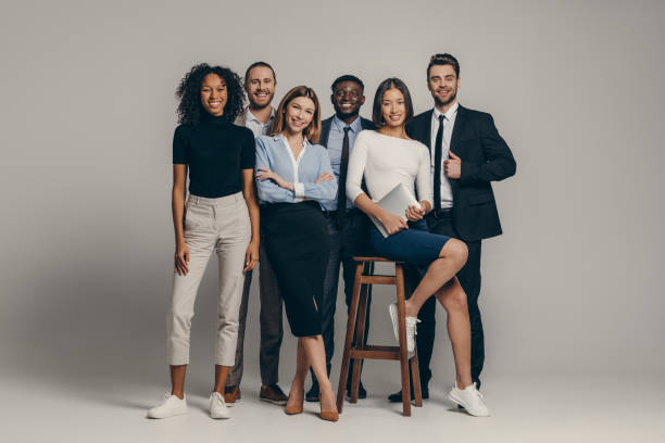 istock Happy young business team in formalwear looking at camera while standing on beige background 1947507596