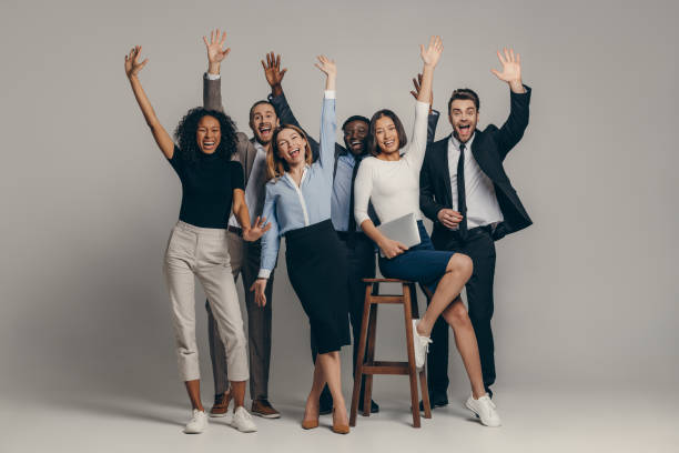 istock Joyful young business team in formalwear gesturing while standing on beige background 1947507611