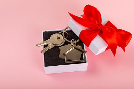 background keychain with keys on an isolated background. Gift house keys. Red bow tied to keys and keychain. Buying, selling a house